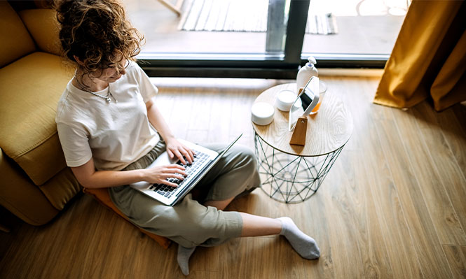 Woman sitting on the floor surrounding by packed boxes.